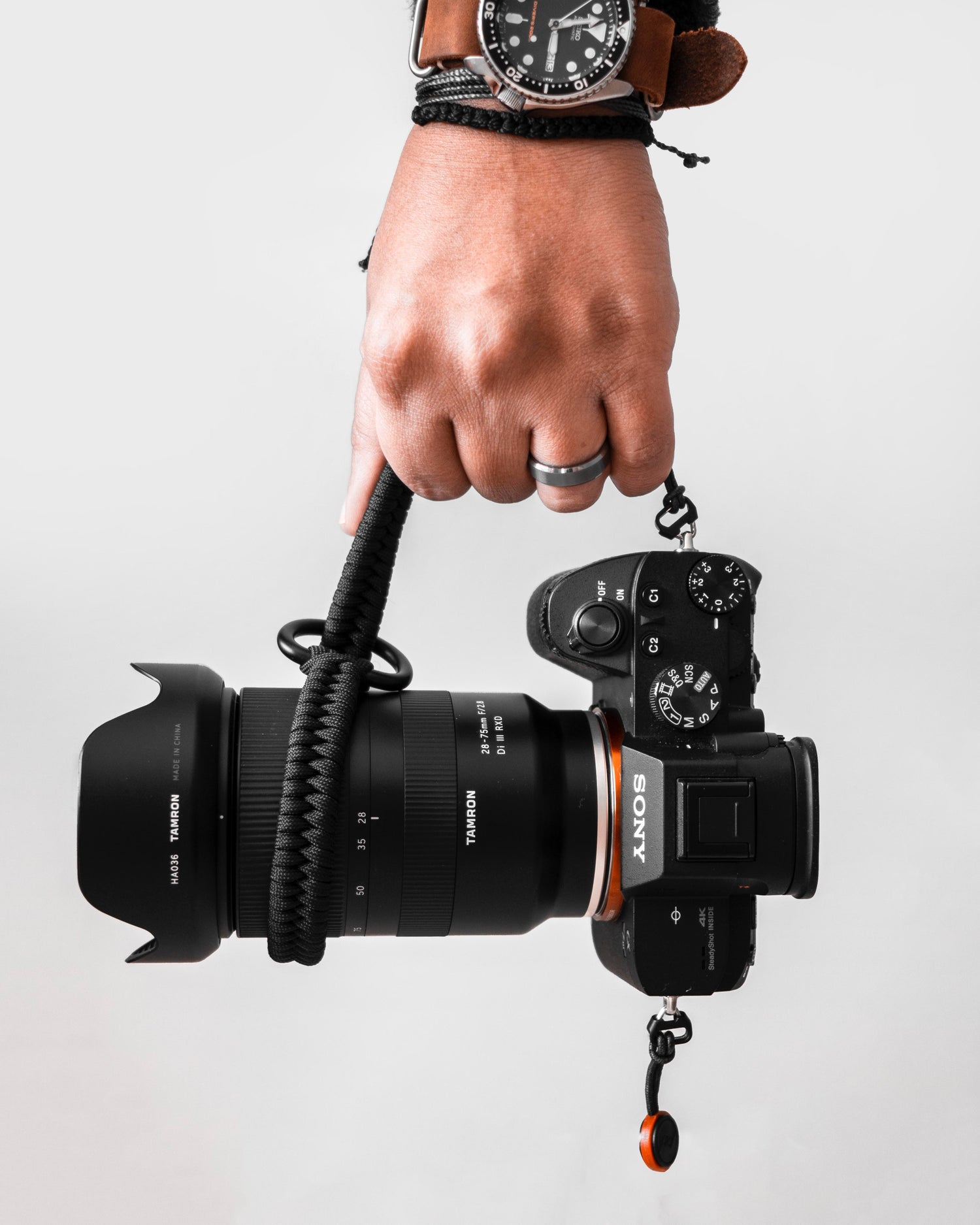 Hand holding a black paracord wrist strap attached to a Sony digital camera